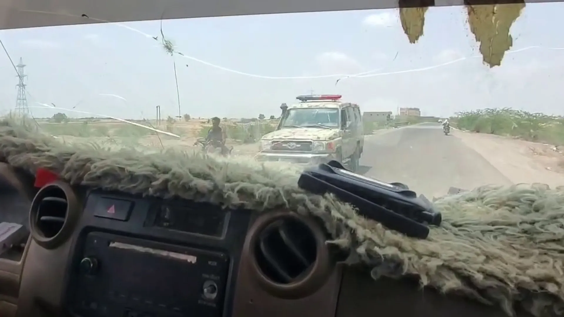 View through a vehicle windshield of a white utility vehicle on a rural road