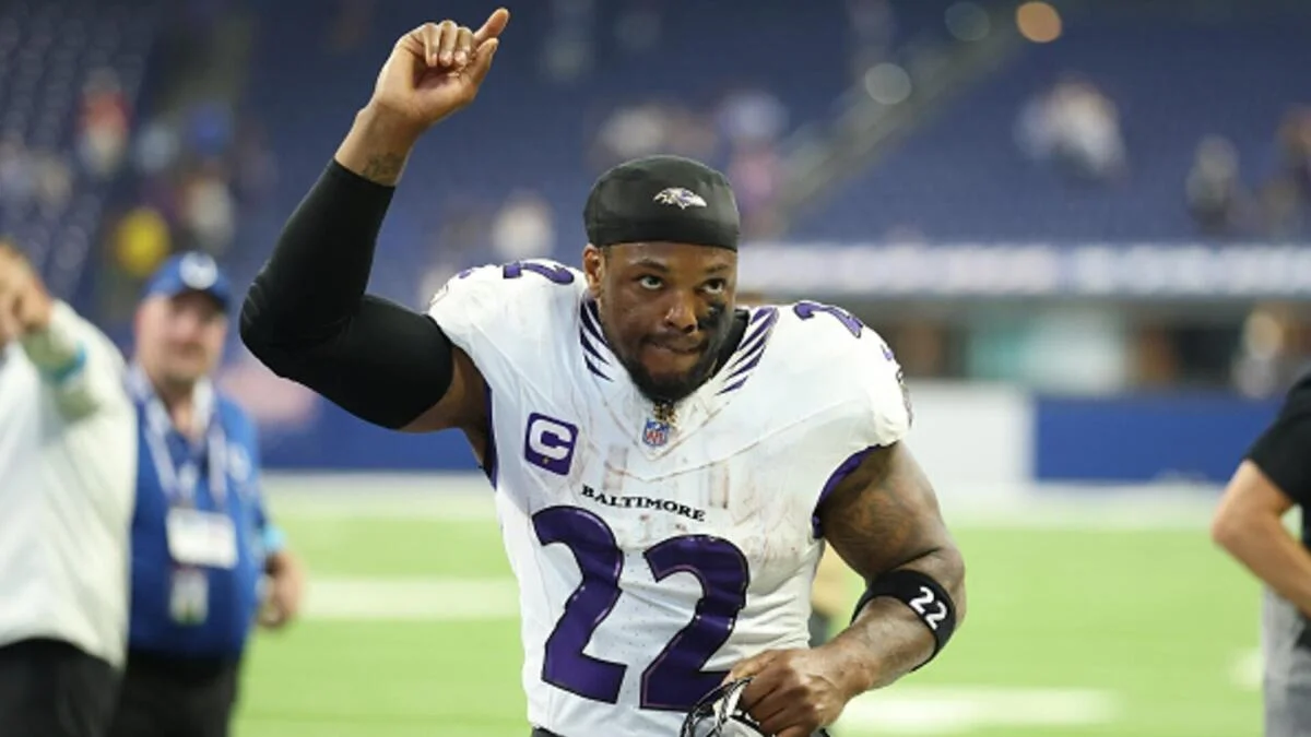 Baltimore Ravens football player wearing number 22 raises one arm during a game.