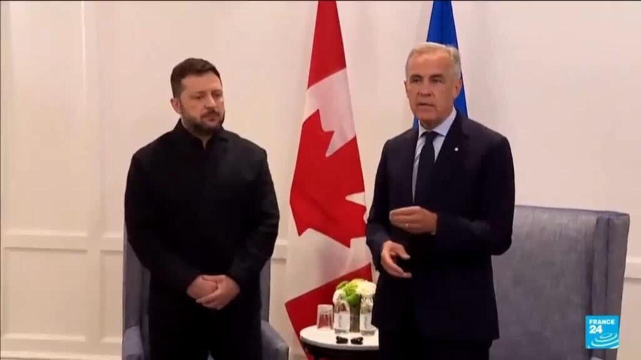 Two officials stand beside Canadian and Ukrainian flags during a formal meeting.