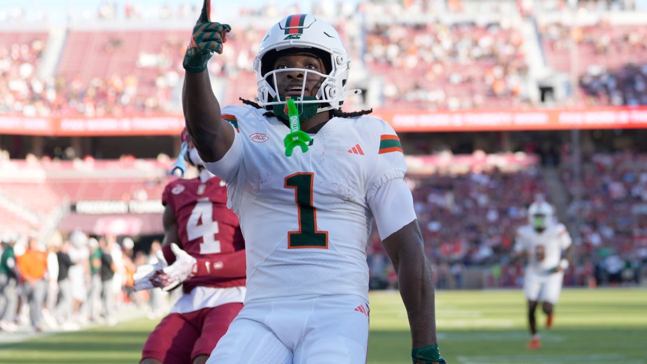 Football player in white uniform and helmet raises one finger during a game