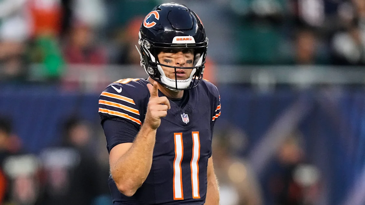 A Chicago Bears player in a navy number 11 uniform points while wearing a helmet and eye black.