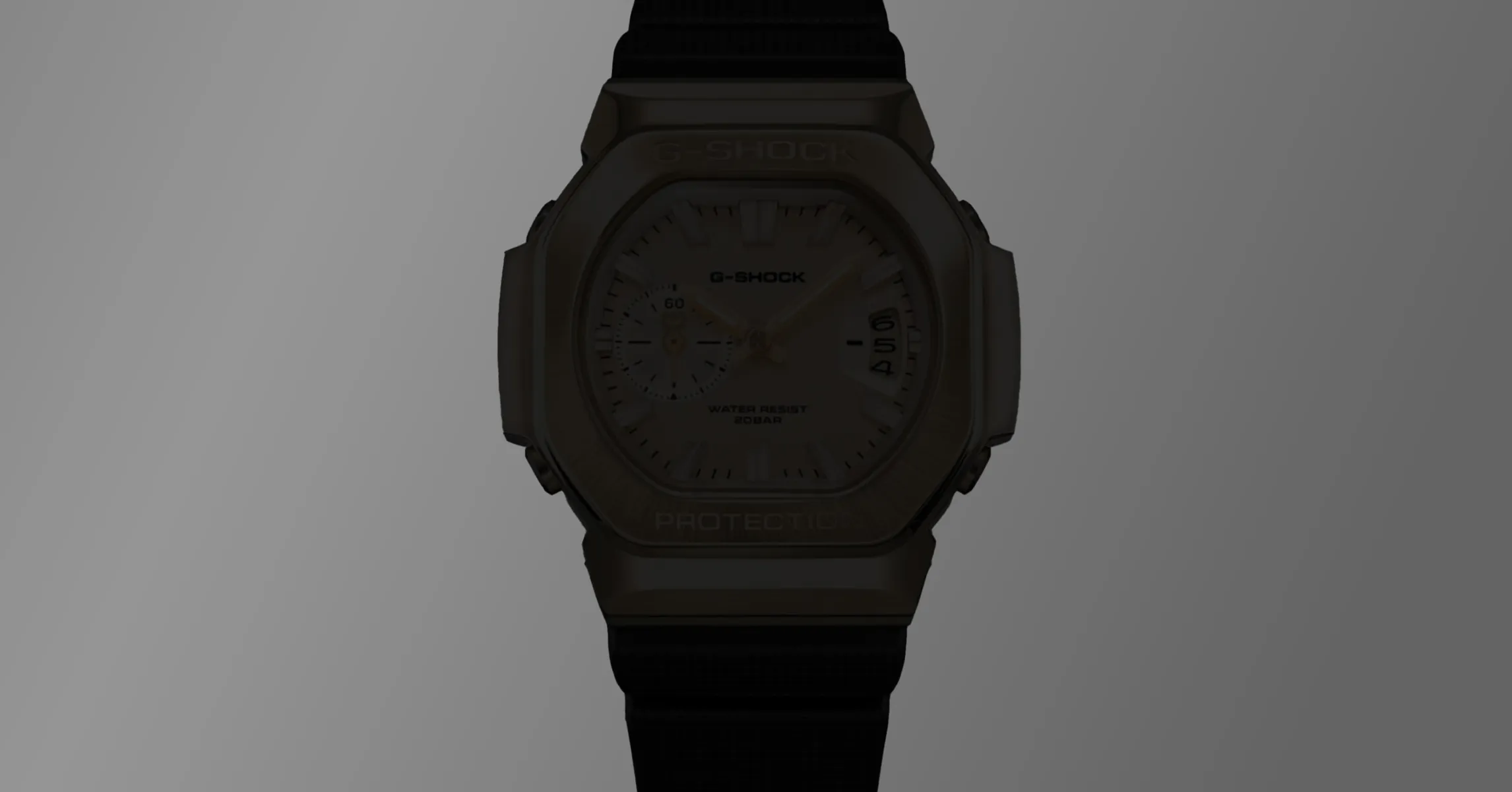 Close-up of a dark G-Shock analog watch with black strap against a gray background