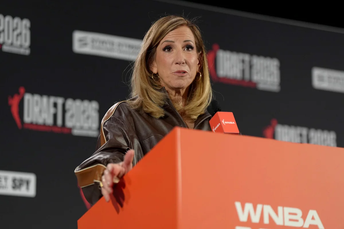 Woman speaking behind an orange WNBA podium at a DraftKings event