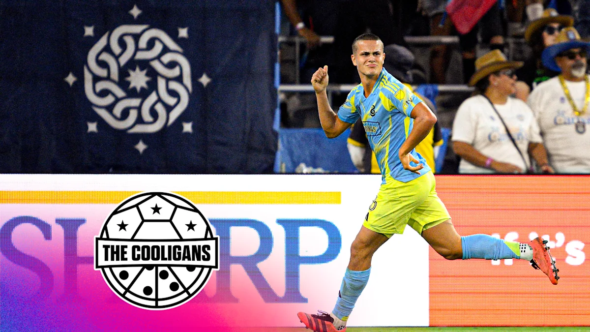 Soccer player in blue and yellow kit celebrates during a match before a crowd.