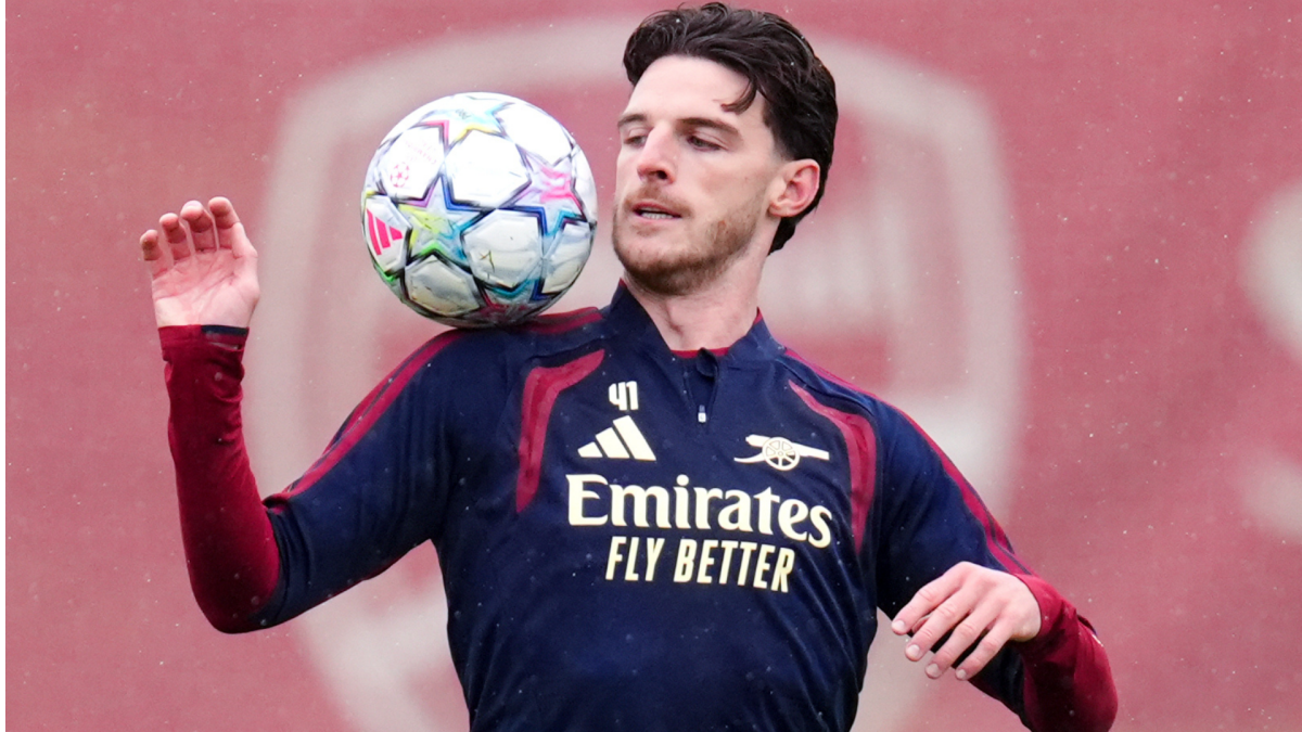 Arsenal footballer balancing a ball during training in front of a red backdrop