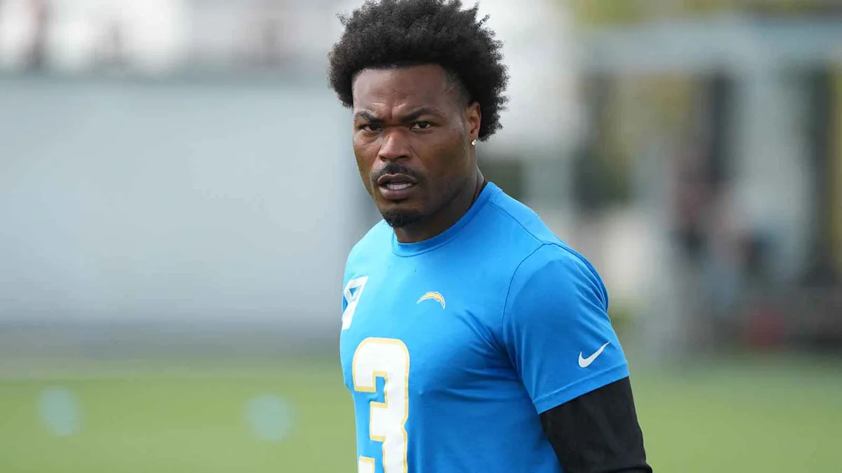 Football player in a blue Chargers jersey stands on a practice field.