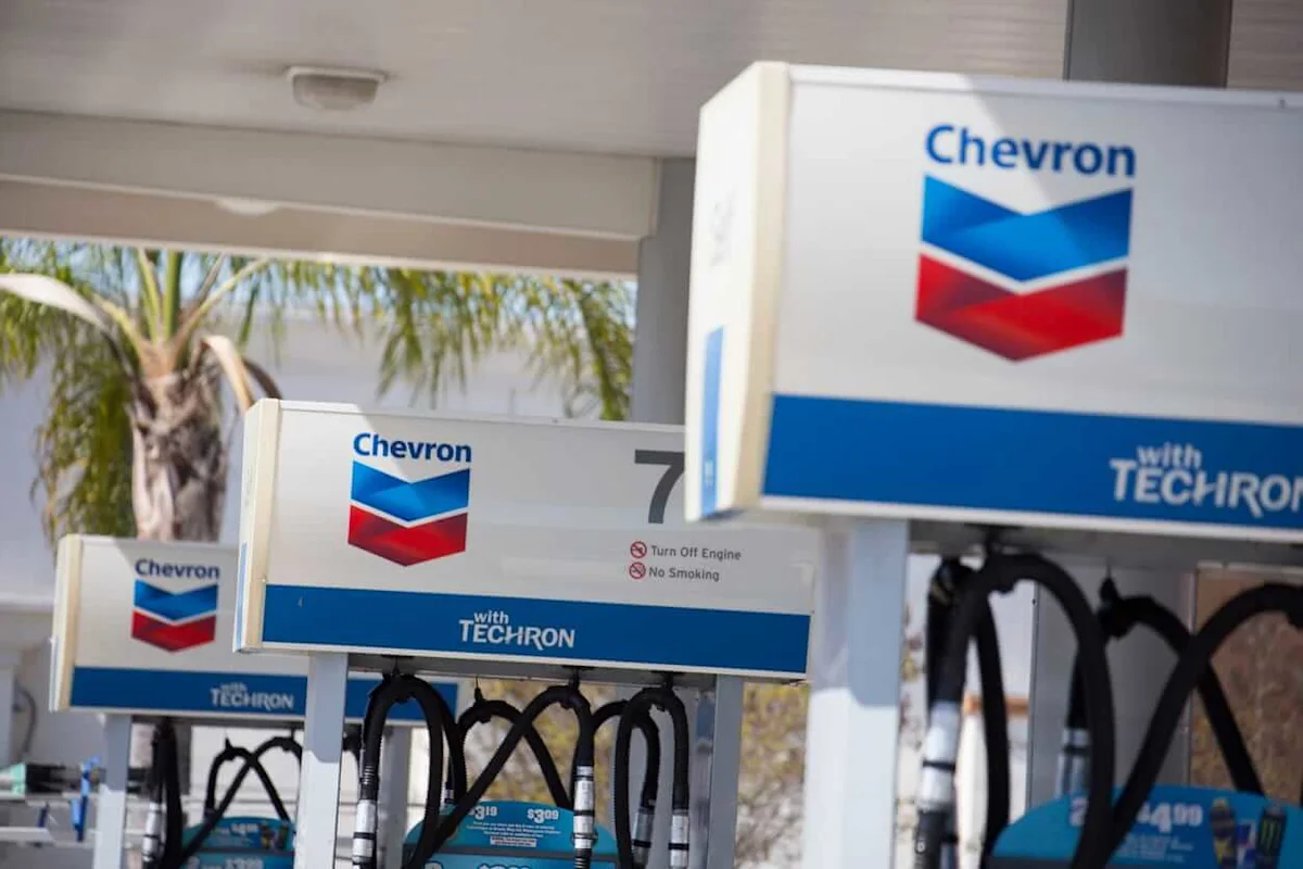 Chevron-branded gasoline pumps with hoses at a fuel station beneath a covered canopy