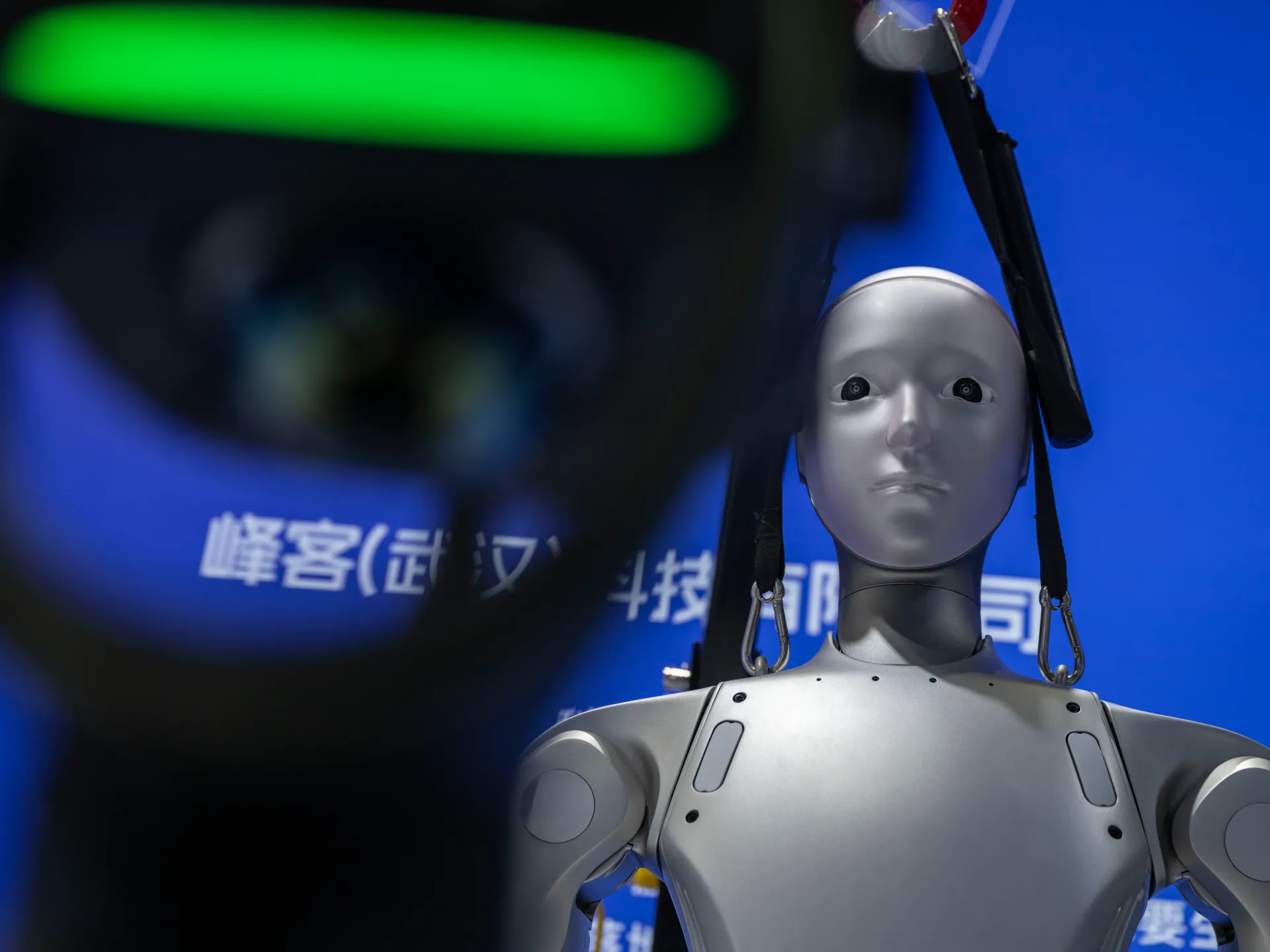 Humanoid robot displayed against a blue backdrop with Chinese characters and dark equipment in the foreground
