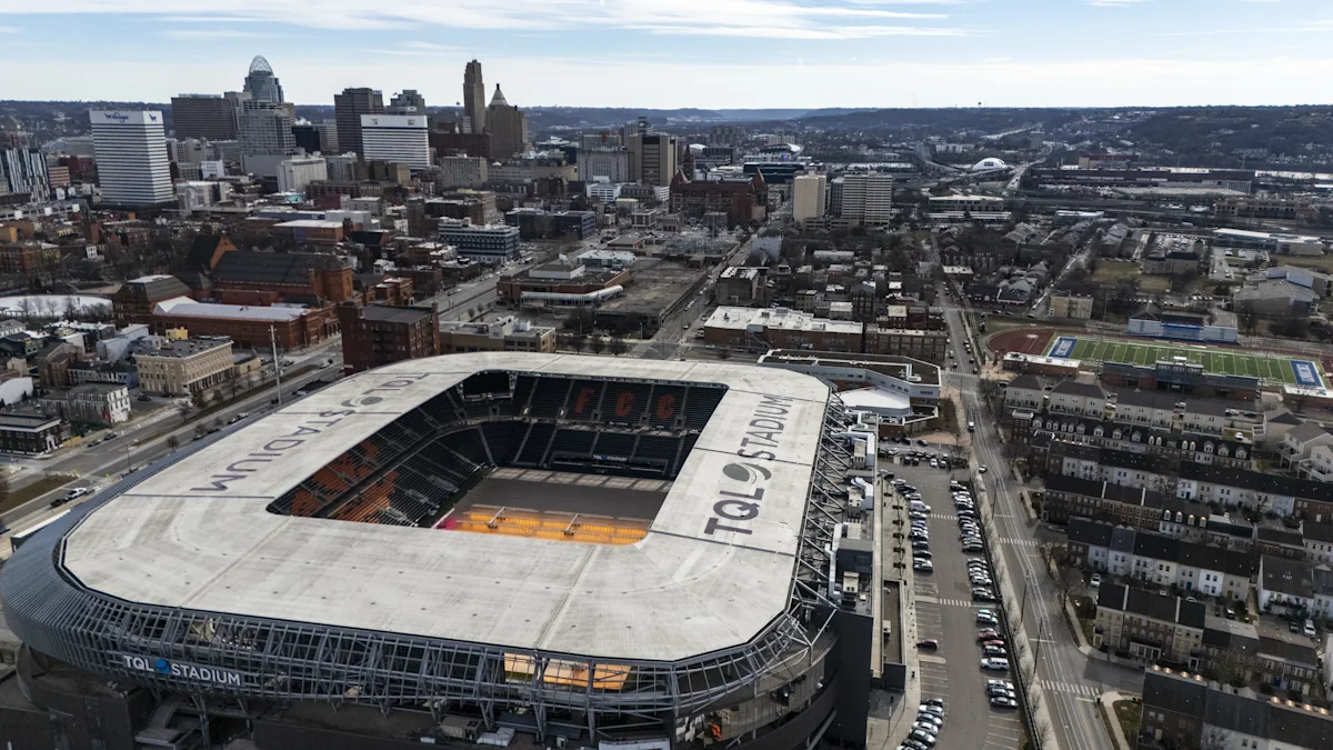 Aerial view of a large stadium surrounded by city buildings and distant hills