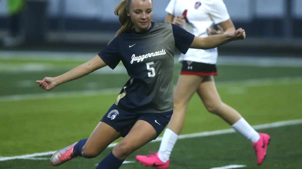 A player in a navy Juggernauts uniform kicks a soccer ball during a match.