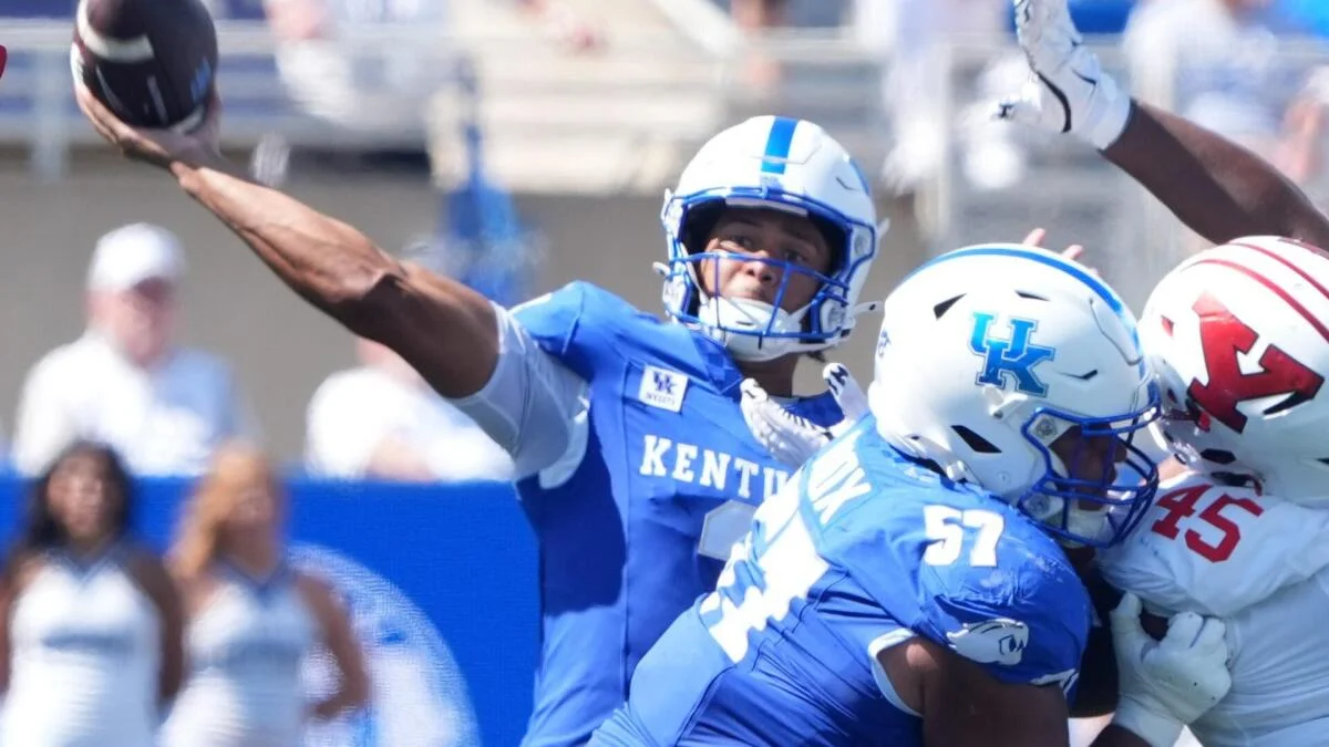 Kentucky quarterback throws a football as players from Kentucky and Iowa State compete nearby