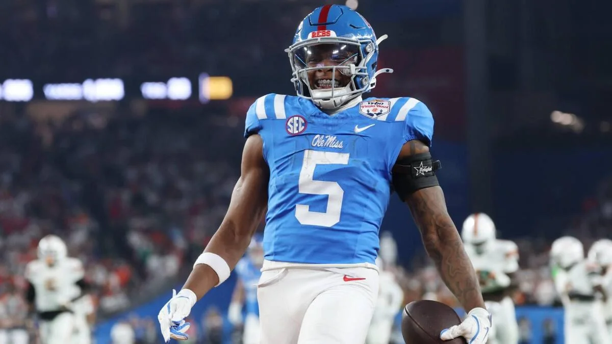 College football player in blue No. 5 uniform holds a football during a game