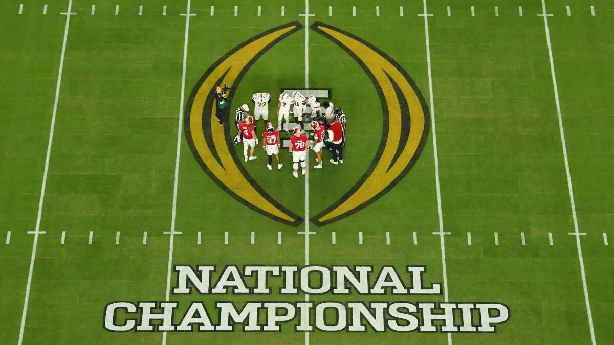 Football players gather at midfield on a field marked with the National Championship logo.