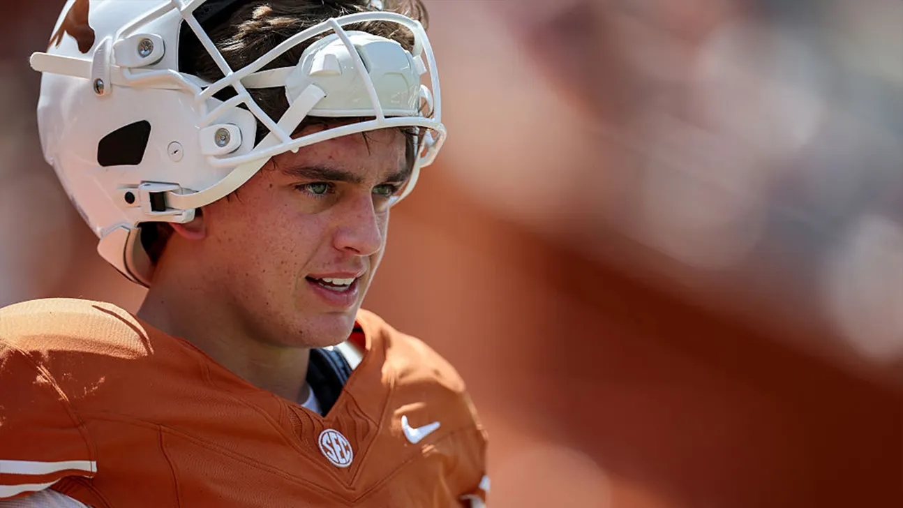 Football player in orange jersey and white helmet looking toward the field