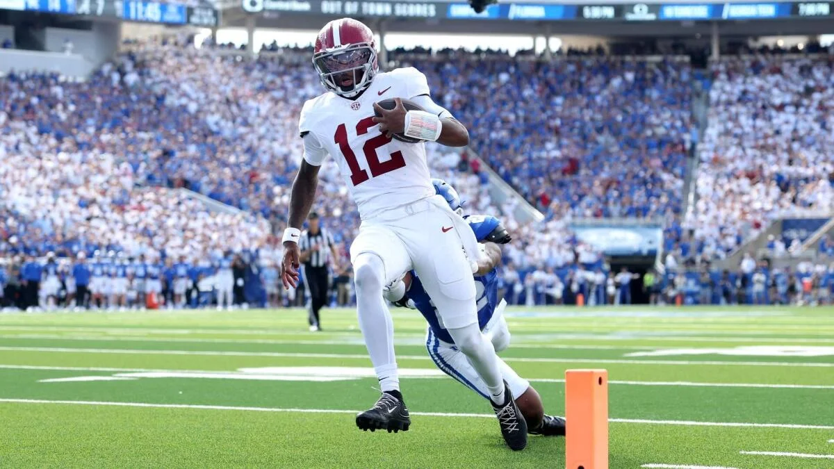 Football player in white uniform runs with the ball near the end zone.