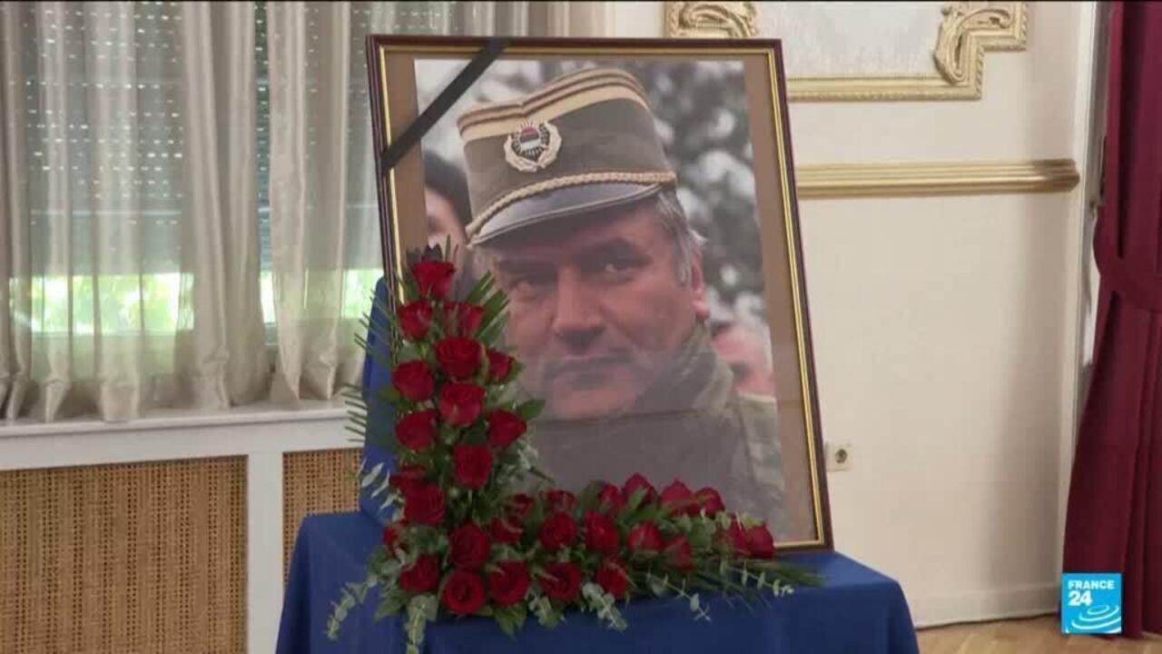 Framed portrait of a uniformed man displayed with black mourning ribbon and red roses