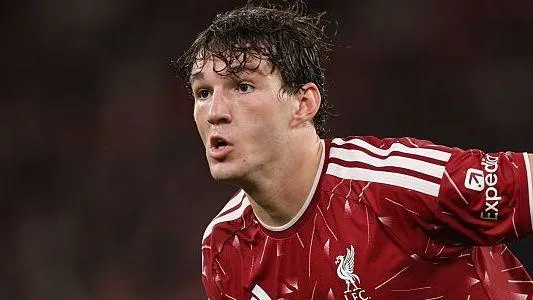Young footballer in a red Liverpool shirt looks to the side during a match.