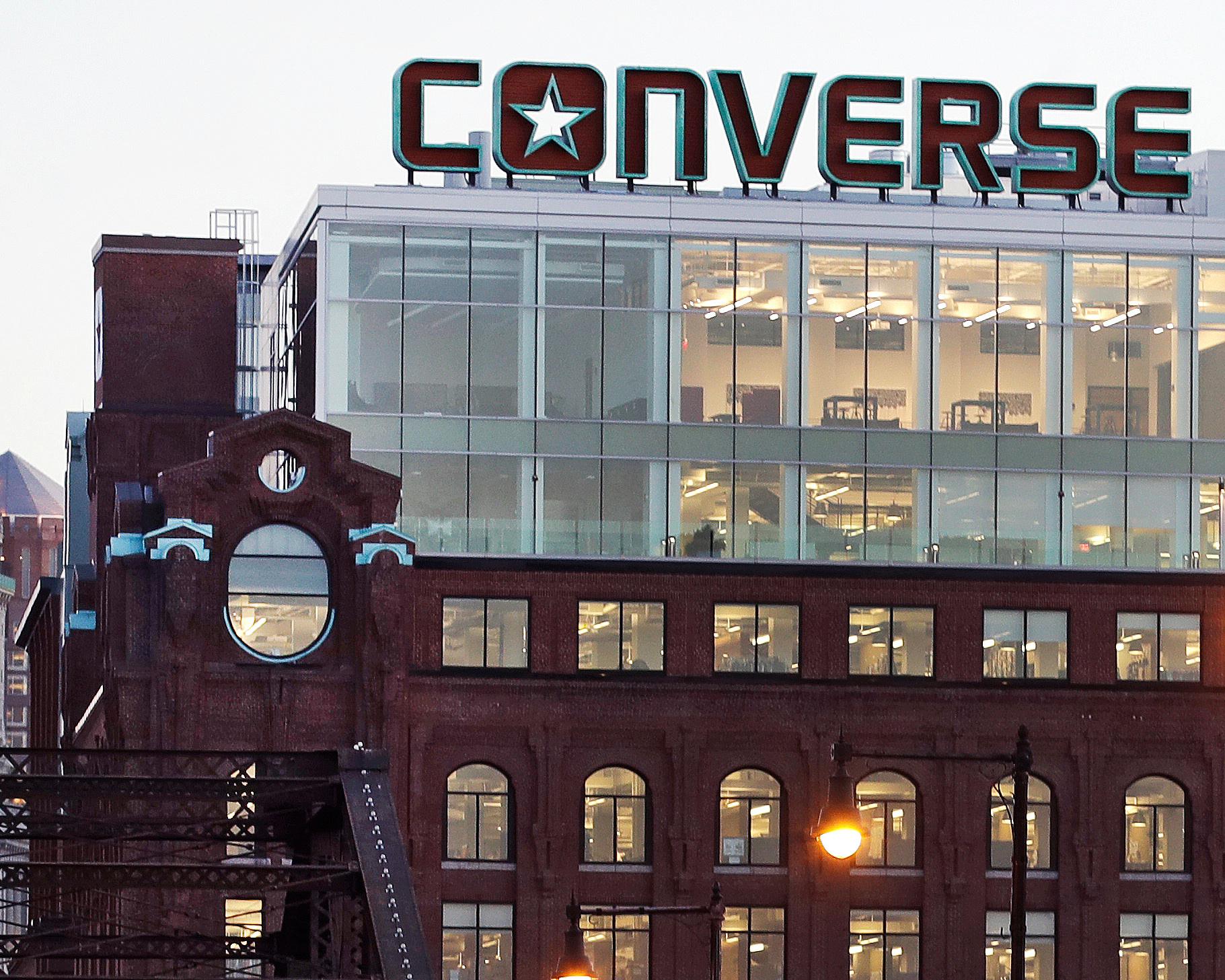 Converse logo mounted atop a multi-story brick and glass building at dusk
