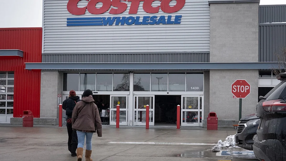 Costco Wholesale entrance with shoppers walking inside on a wet day.