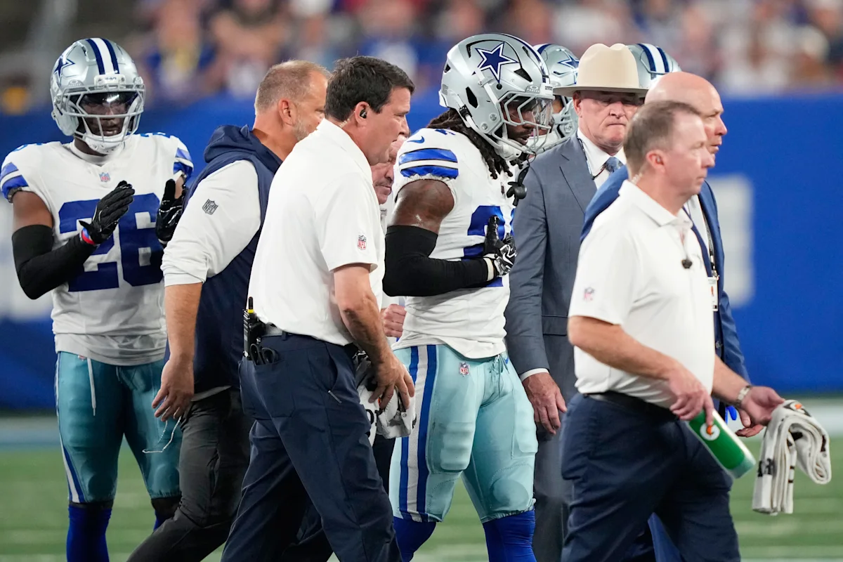 Dallas Cowboys players and staff gather on the sideline during an NFL game.