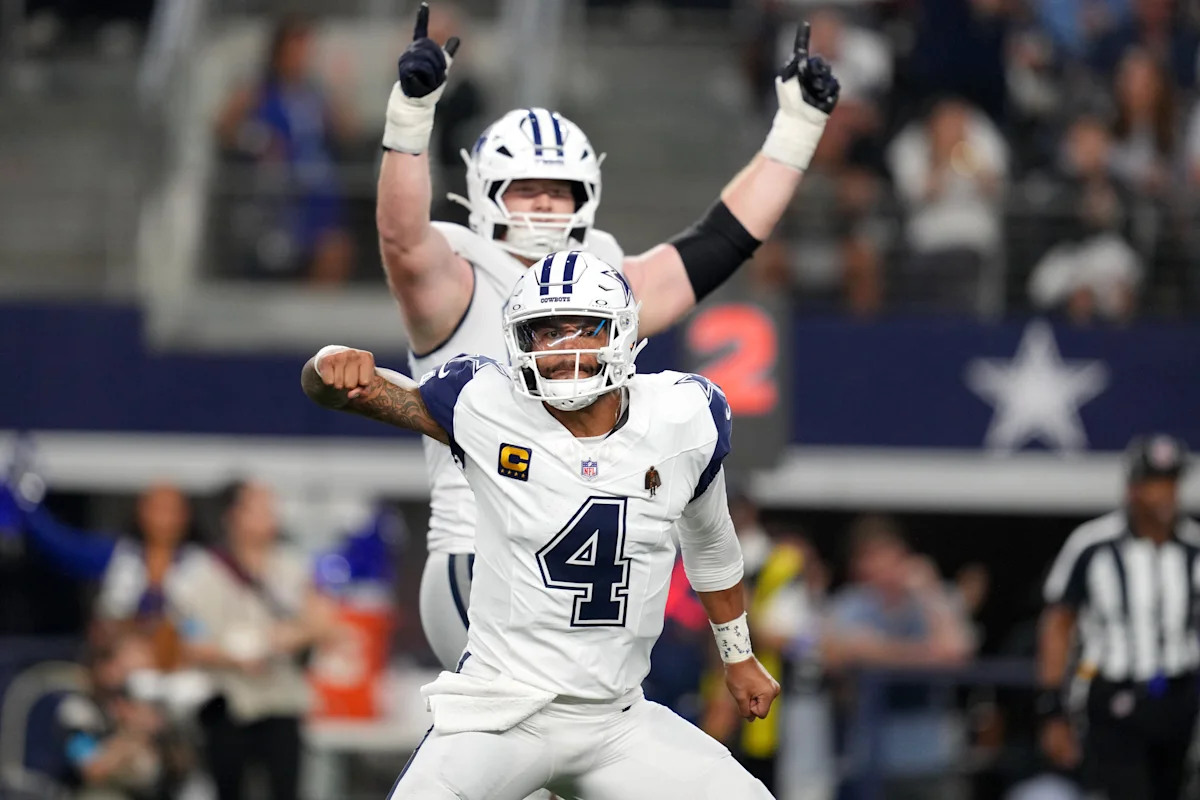 Dallas Cowboys quarterback in white No. 4 jersey celebrates with teammate during football game