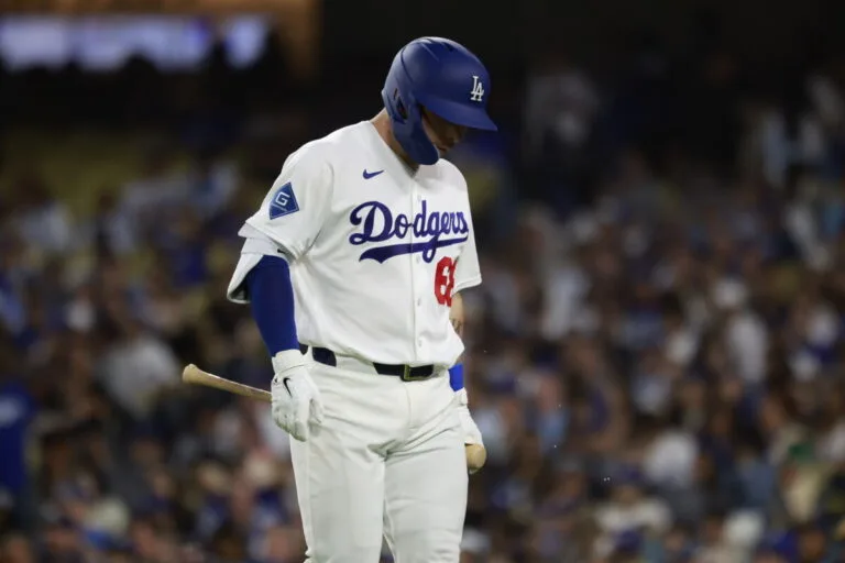 Dodgers baseball player in white uniform and blue helmet walking with bat