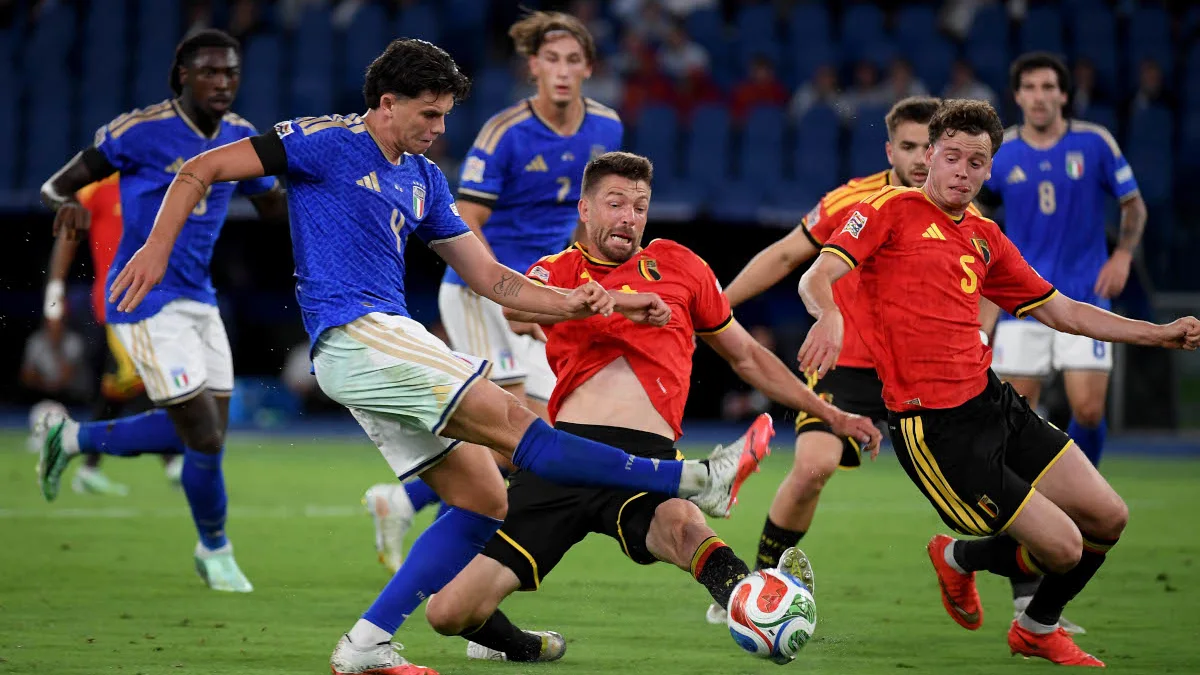 Italy players in blue challenge Belgium players in red for the ball during a football match.