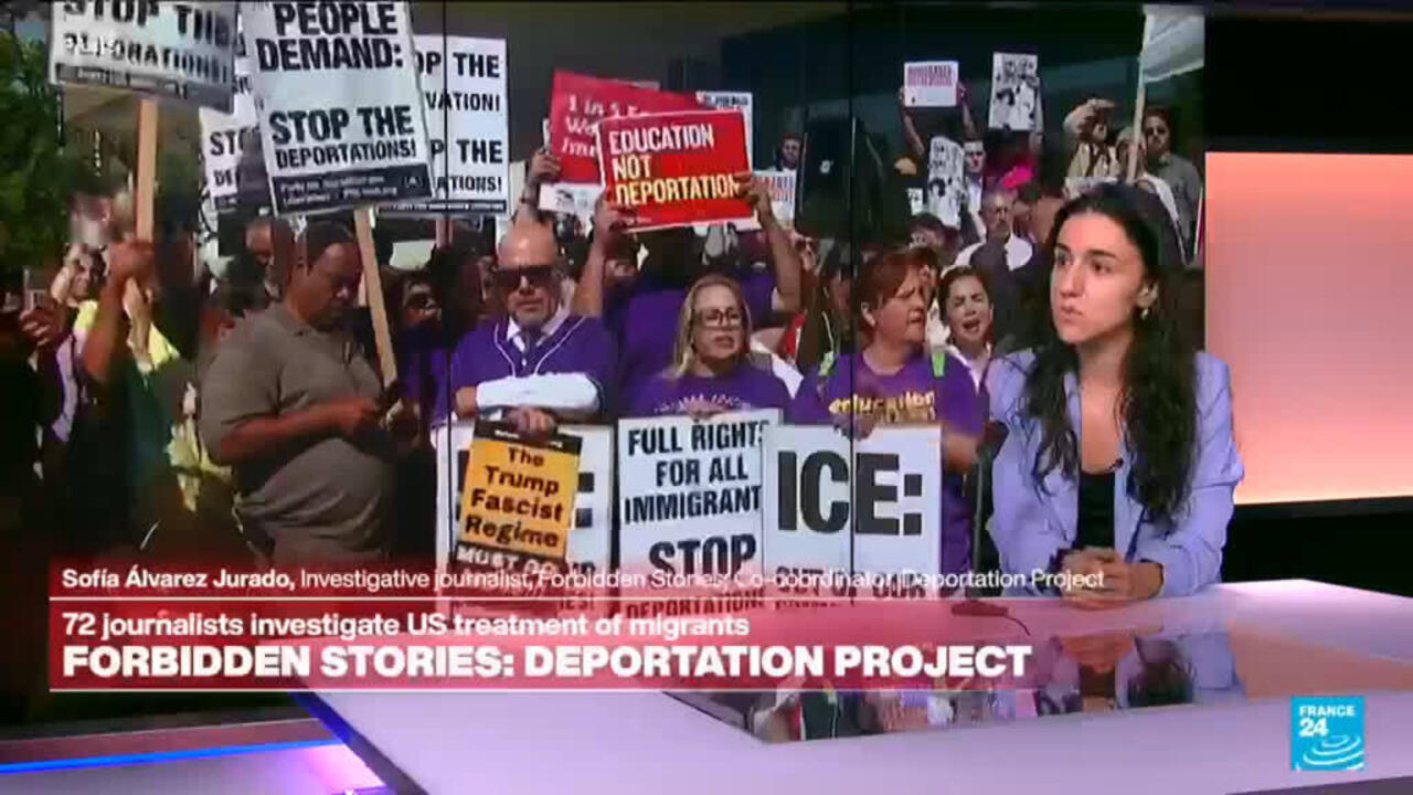 Television interview shows journalist beside protesters holding anti-deportation and immigrant rights signs.