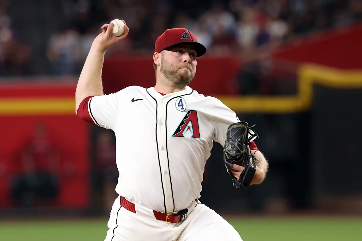 Baseball pitcher in Diamondbacks uniform winds up to throw during a game.