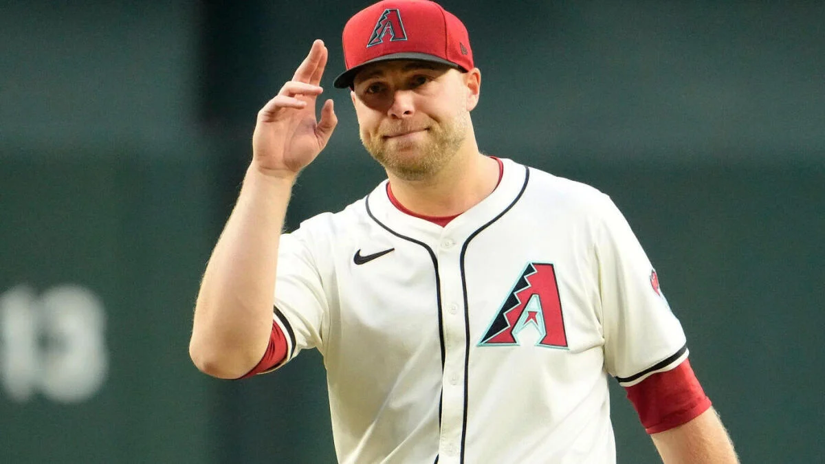 Baseball player in Diamondbacks uniform and red cap raising his hand during a game