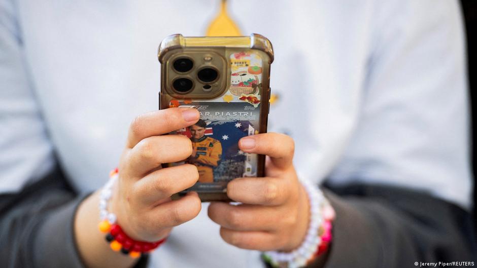 Person holding a decorated smartphone, with colorful bracelets visible on both wrists.