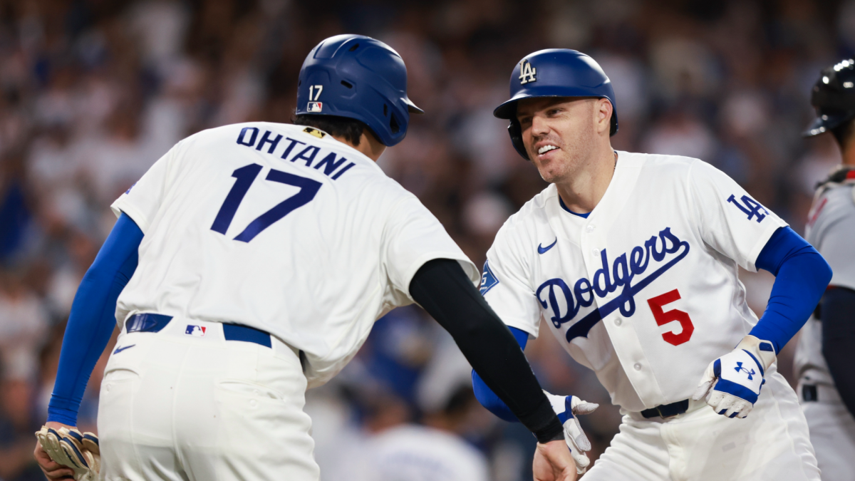 Two Los Angeles Dodgers players in white uniforms celebrate near home plate during a game.