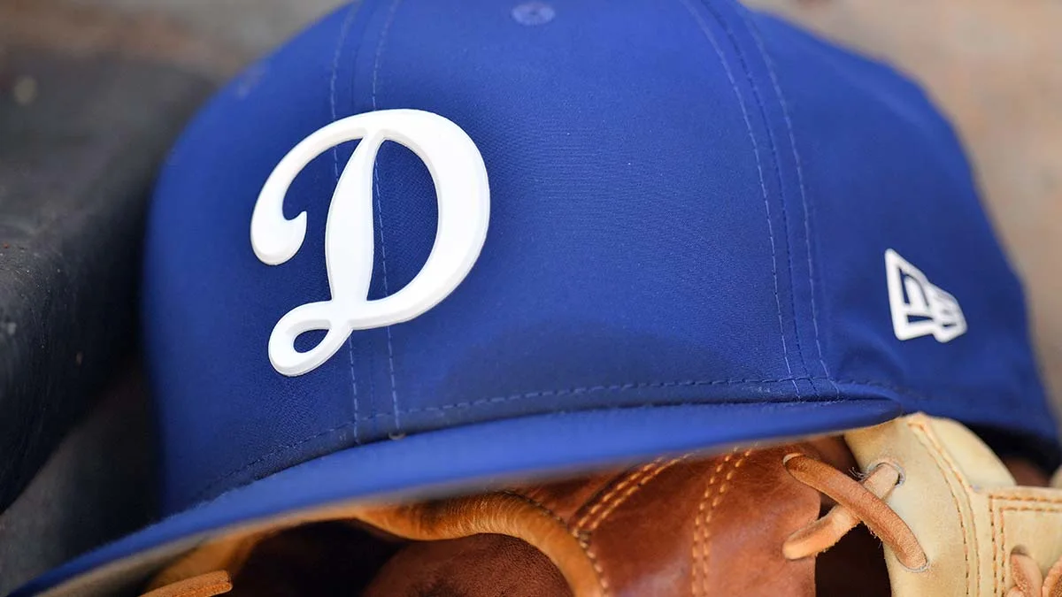 Close-up of a blue Los Angeles Dodgers cap resting over a brown baseball glove.