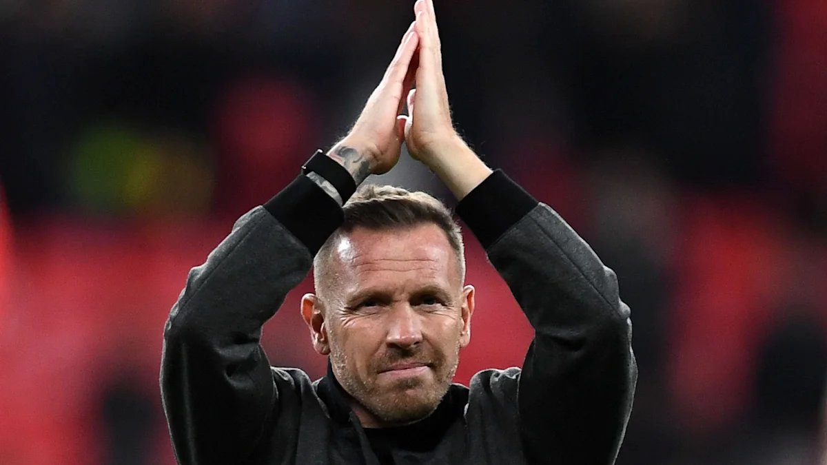 Man in dark clothing applauding with hands raised above his head