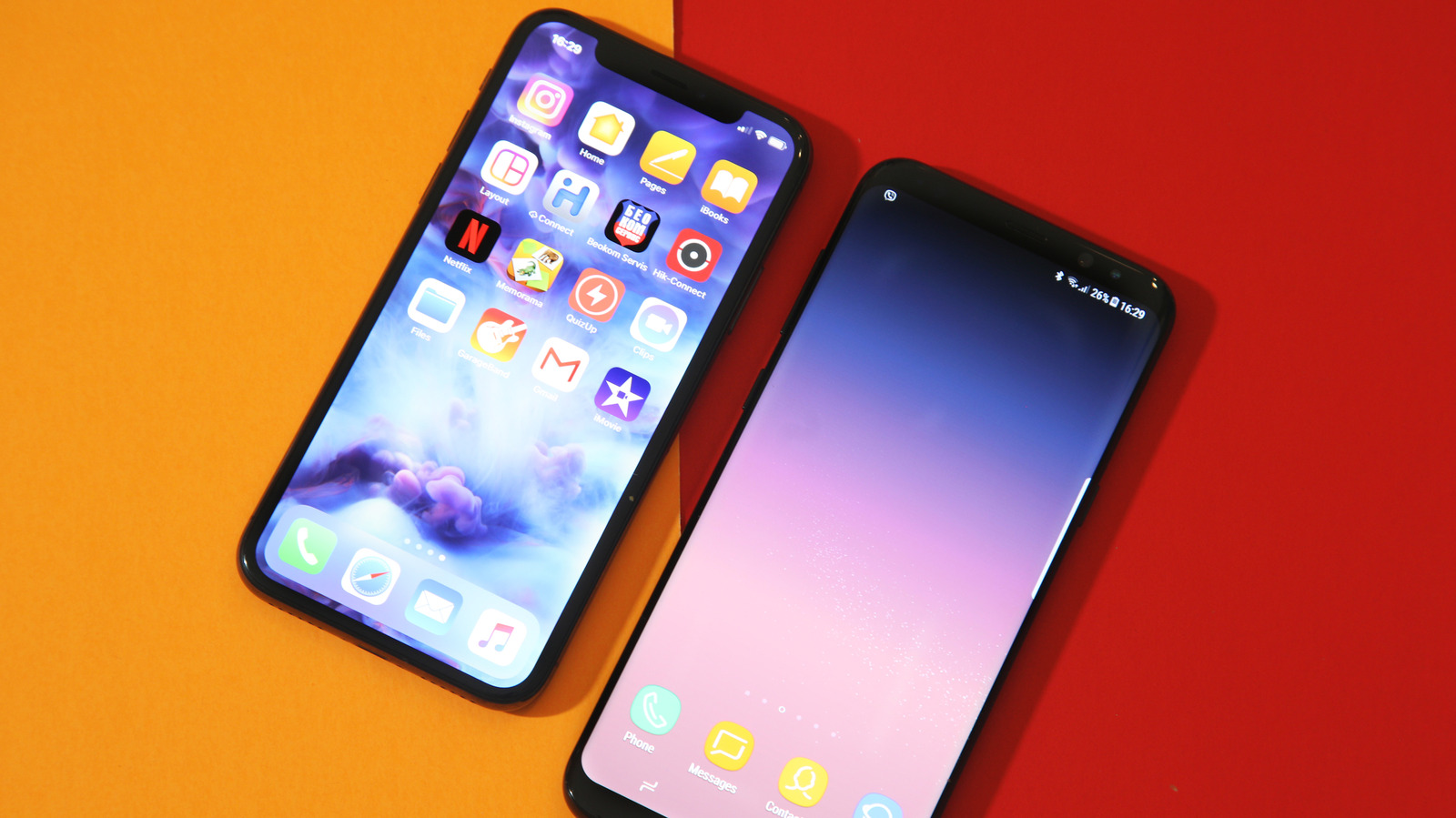 Two smartphones lie diagonally on an orange and red surface, displaying colorful home screens.
