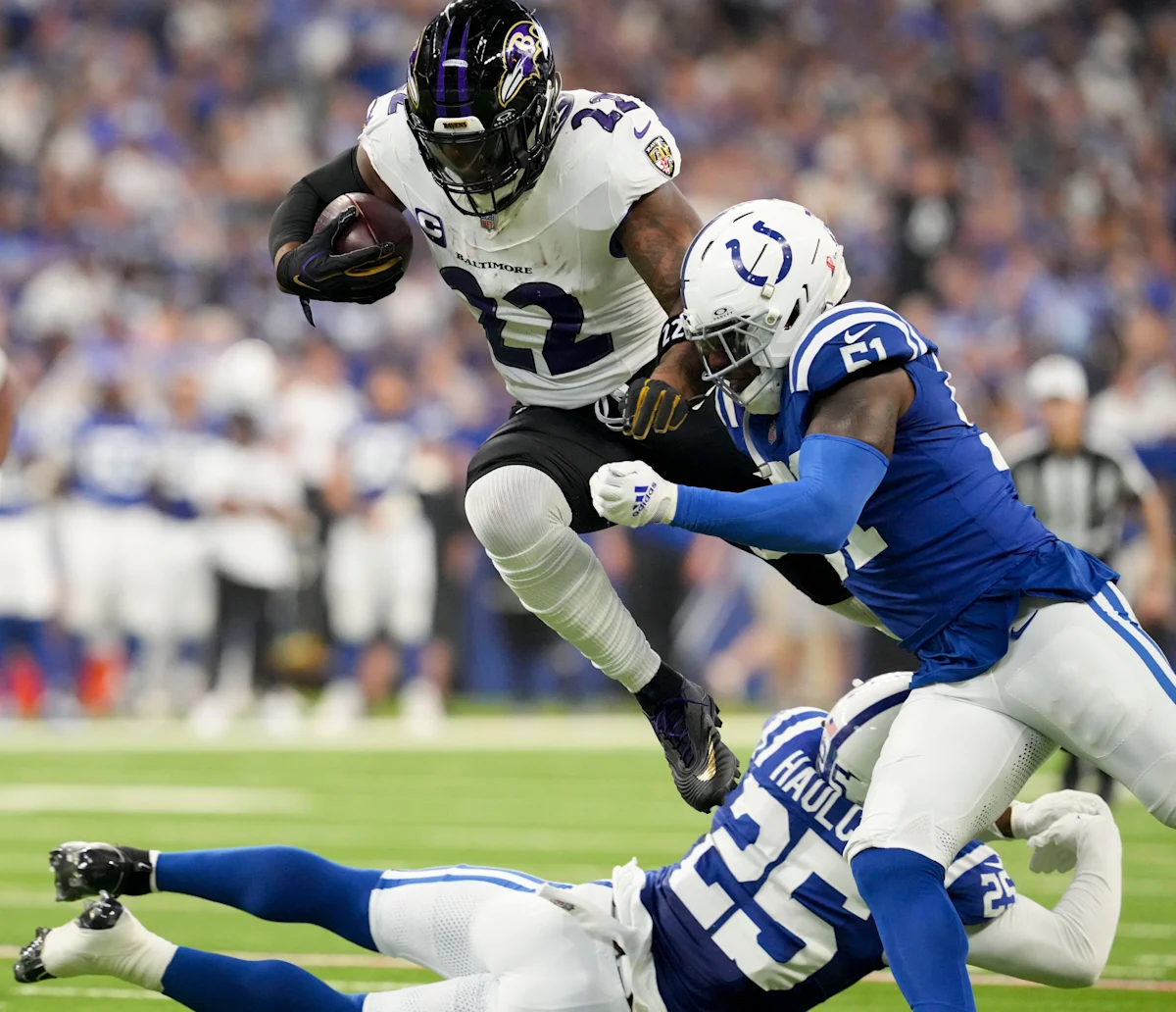 Baltimore ball carrier leaps past Indianapolis defenders during an NFL game