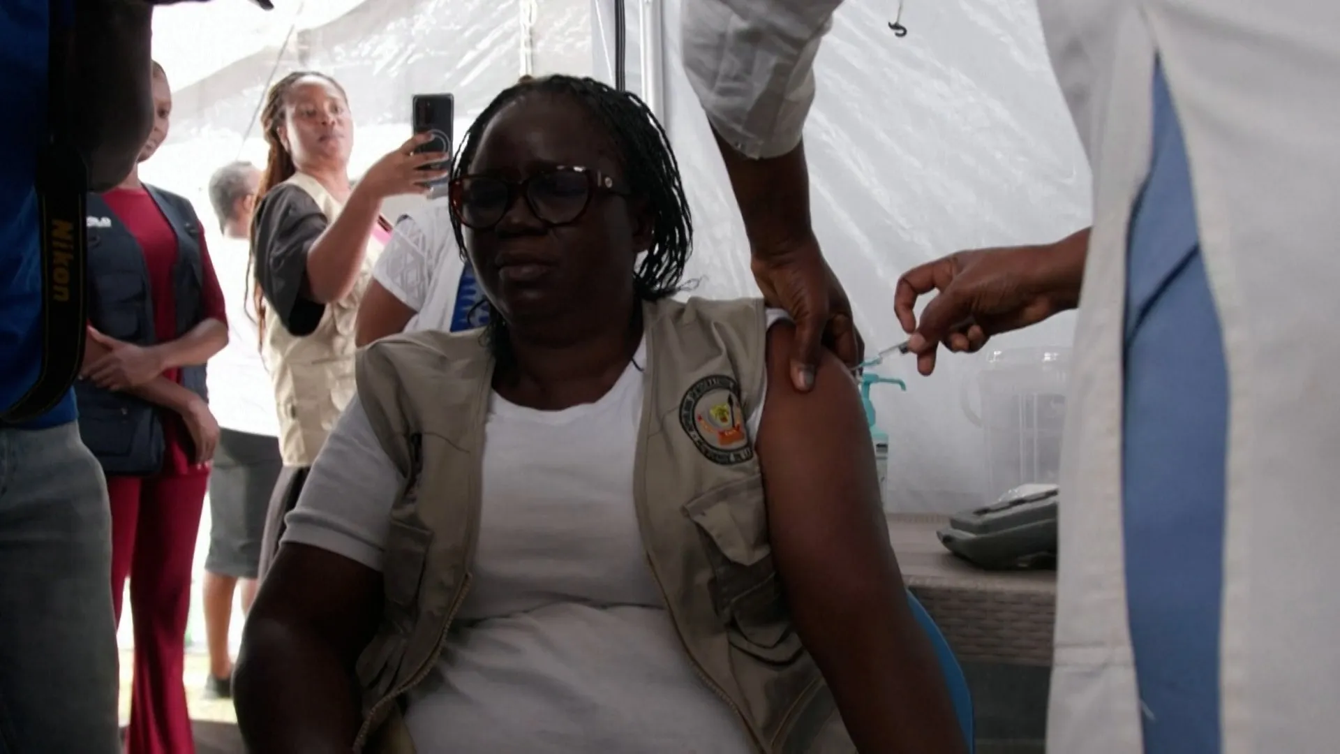 Health worker receives an injection on the upper arm inside a temporary medical tent