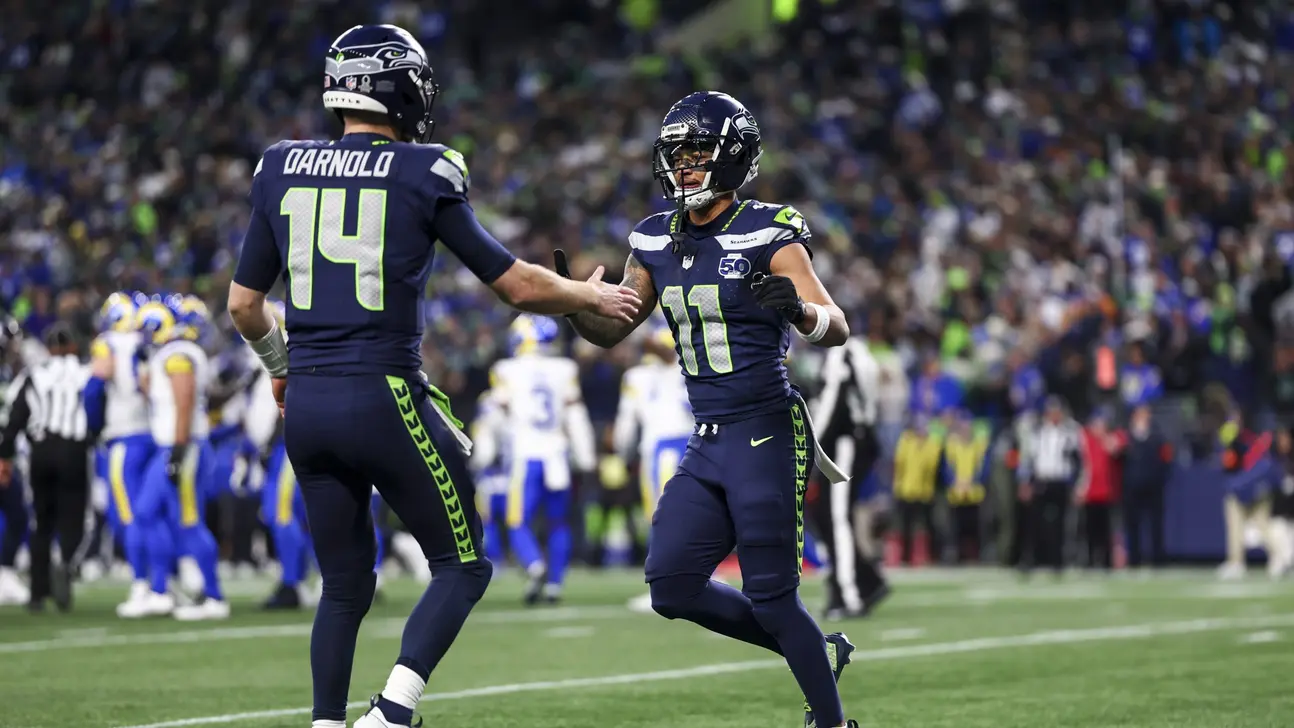 Seattle football players in navy uniforms meet on field during a game