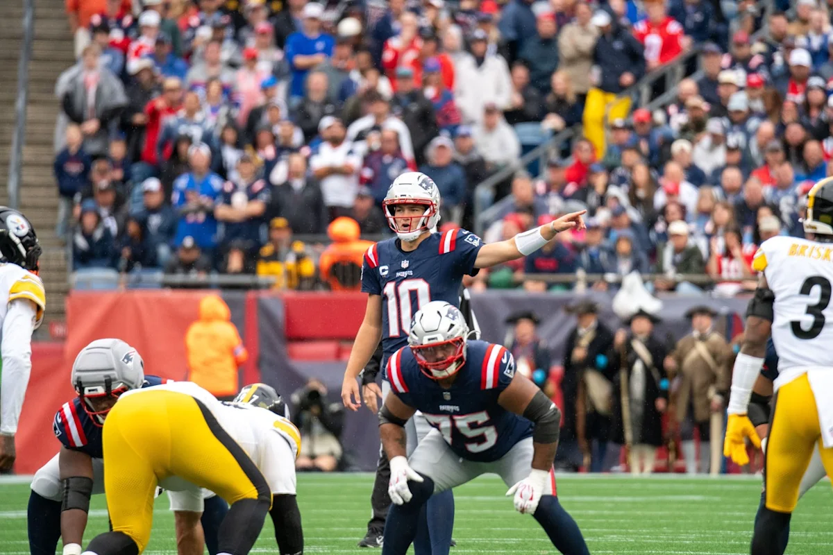 Patriots quarterback points before a play as teammates line up against Steelers defenders.