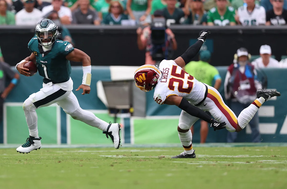 Eagles quarterback runs with the ball as a Washington defender dives toward him.