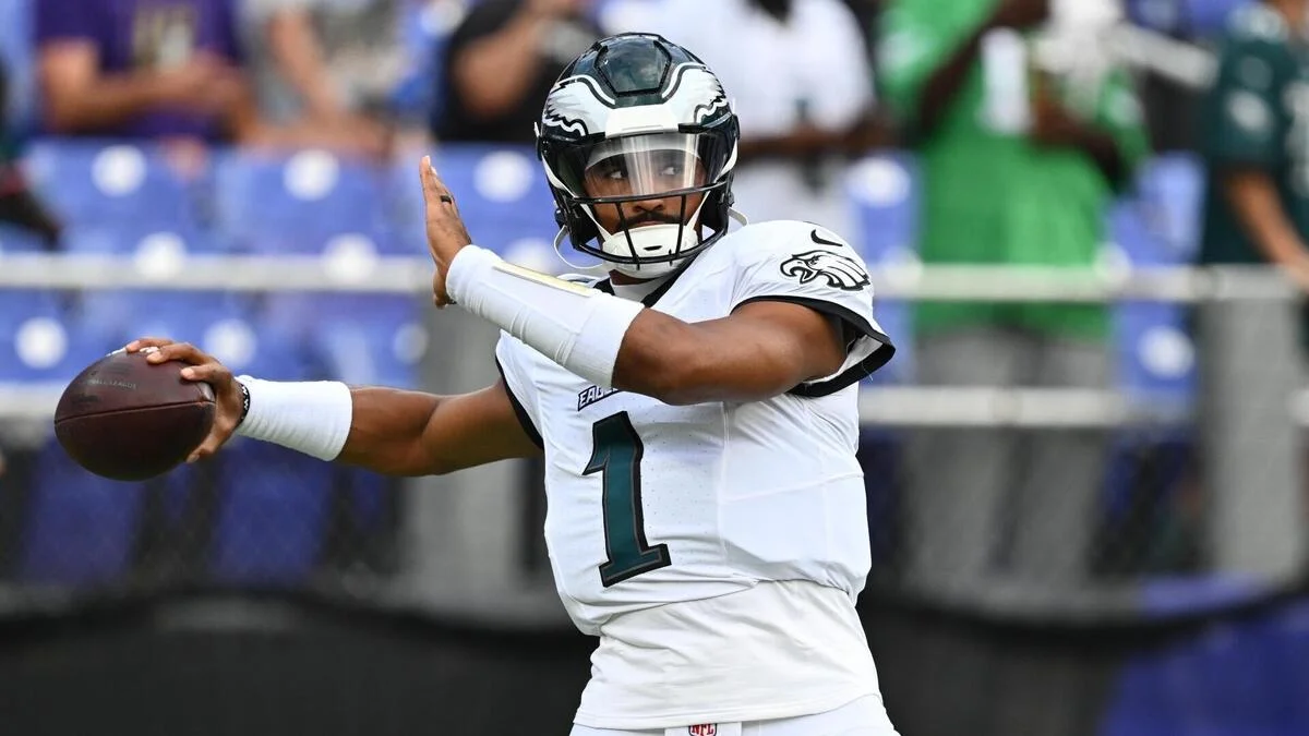 Philadelphia Eagles player in a white number 1 uniform holds a football while preparing to throw.