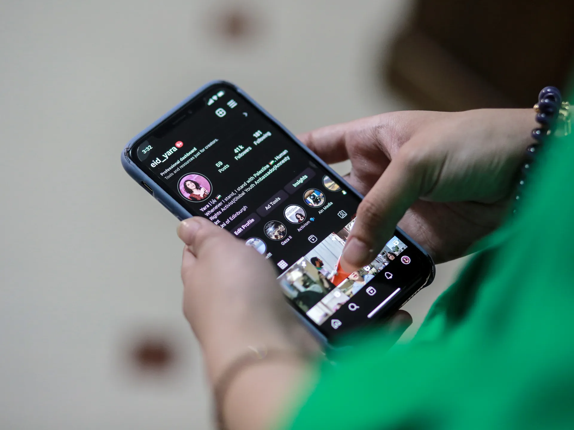 Person holding a smartphone displaying an Instagram profile and grid of posts
