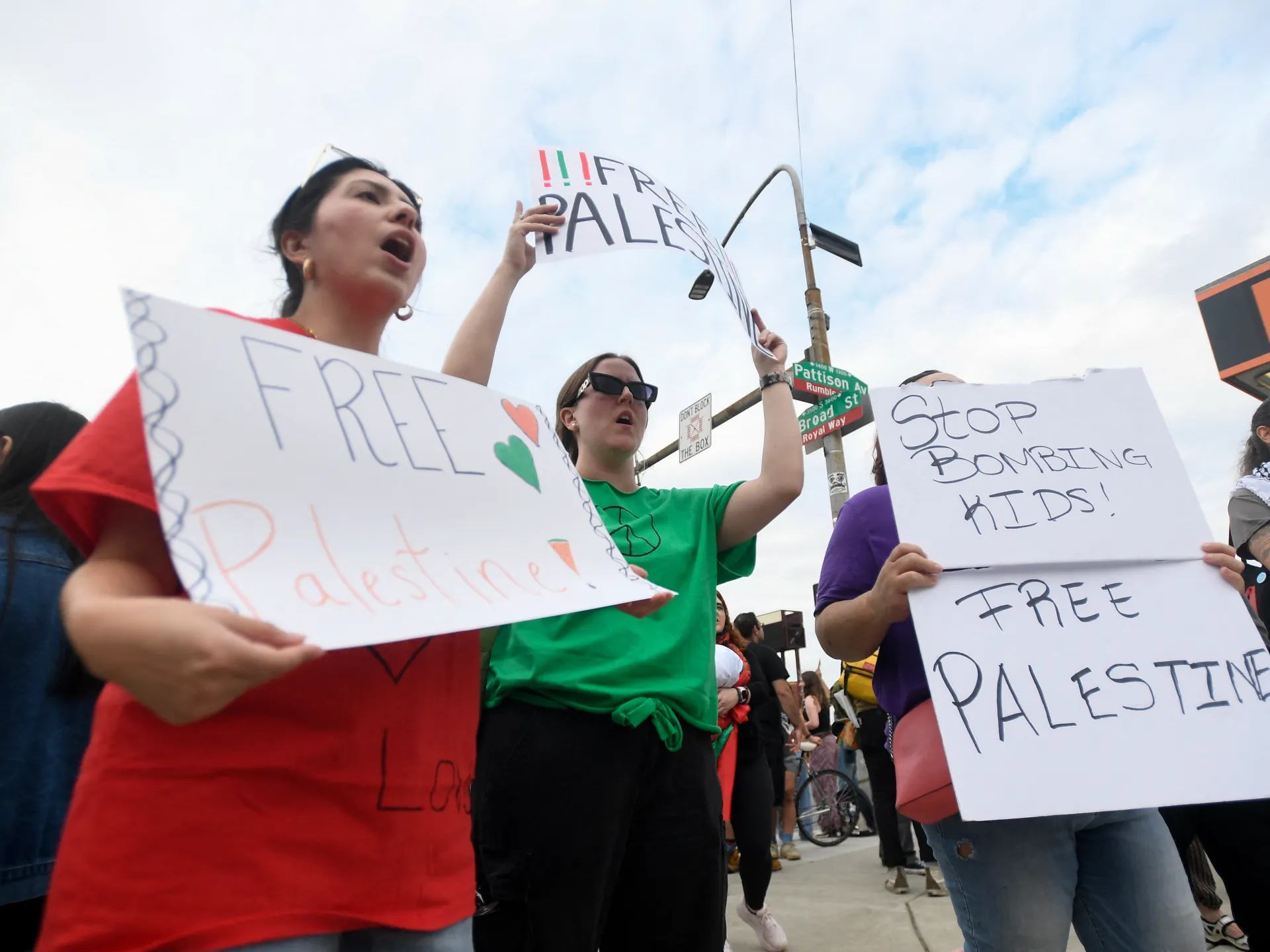 Protesters hold handwritten signs calling for Palestinian freedom and an end to bombing.