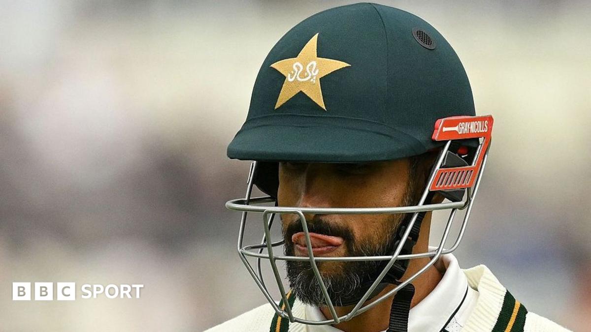 Cricketer wearing a dark helmet and face guard, with tongue visible, shown in close-up