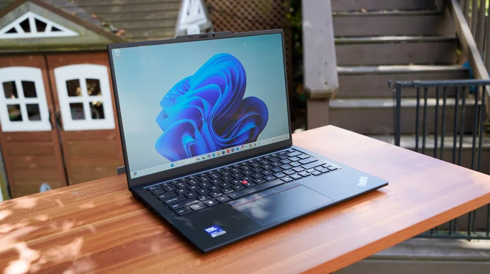 Lenovo ThinkPad laptop open on a wooden outdoor table with Windows 11 displayed