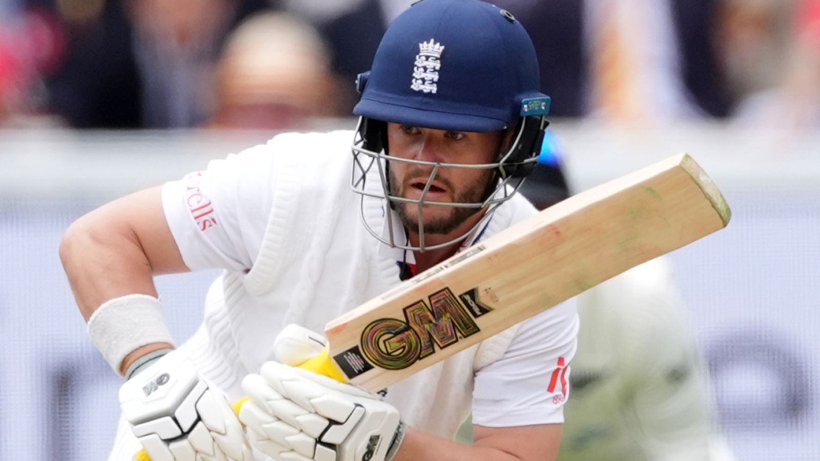 England batsman in helmet and white kit holds his bat during a Test match