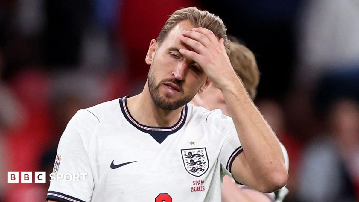England player in a white shirt presses a hand to his forehead during a match.
