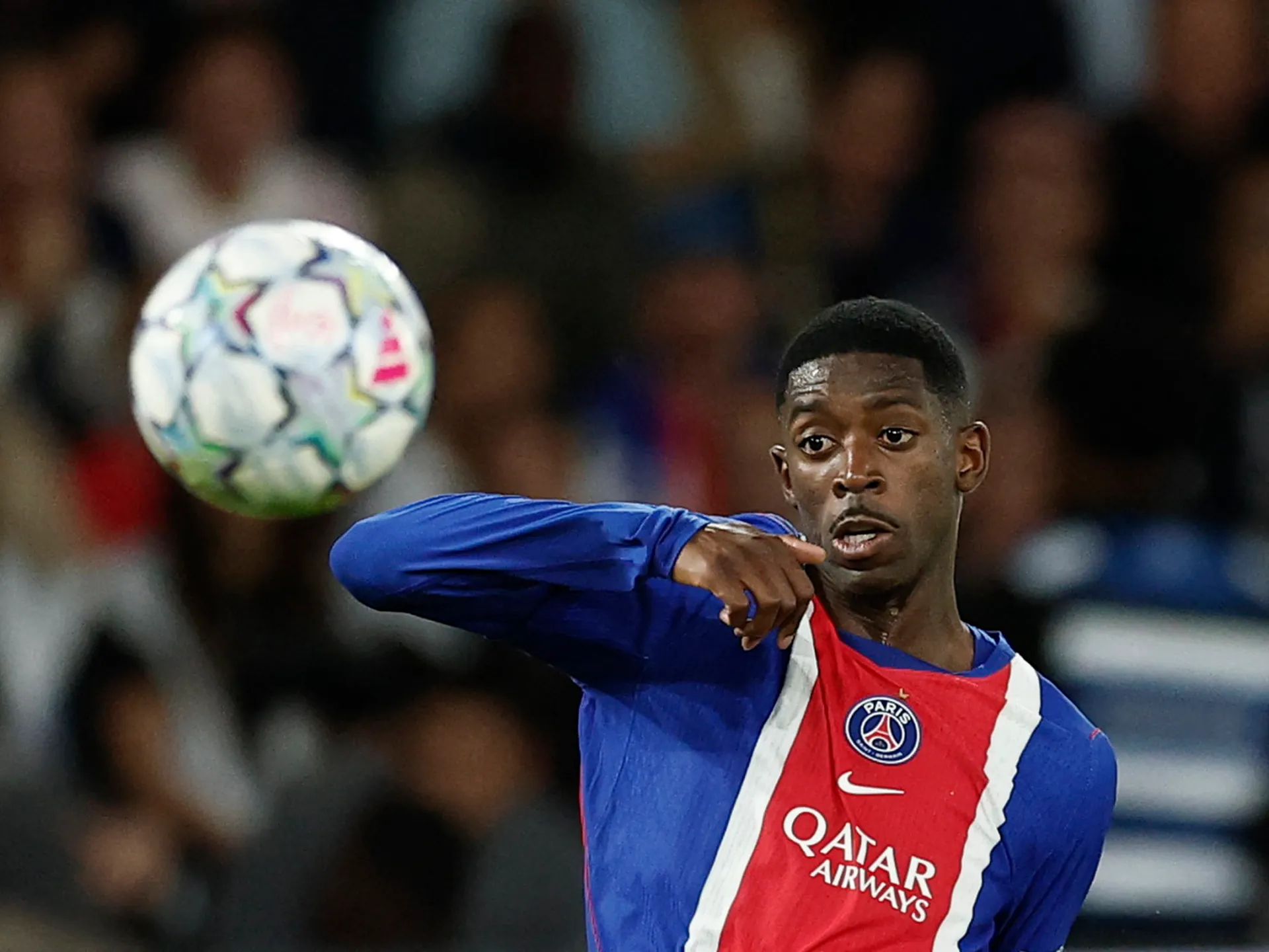 PSG player in blue and red kit watches a football during a match