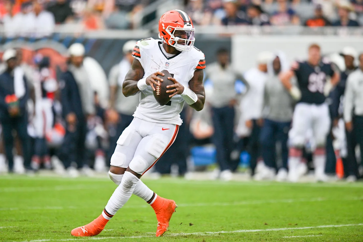 Football quarterback in Browns uniform running with the ball during a game