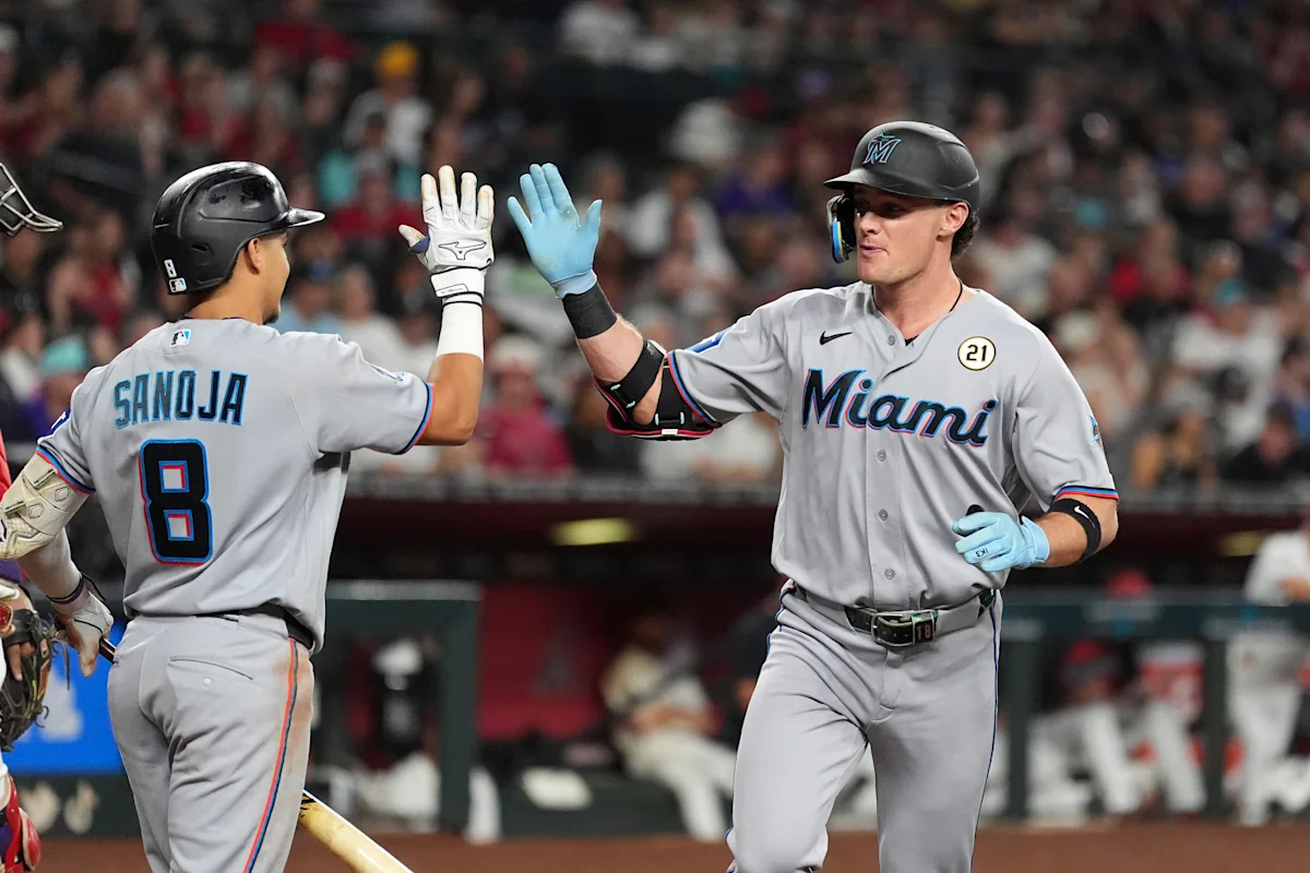 Miami Marlins players exchange a high-five during a baseball game.